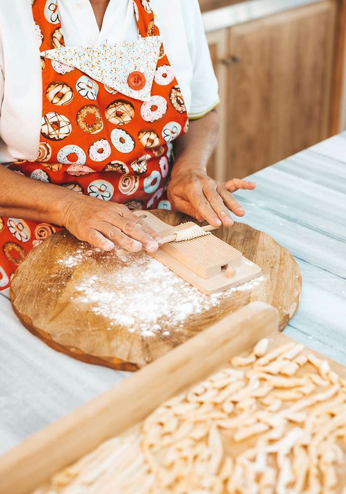 a person in an apron making pasta
