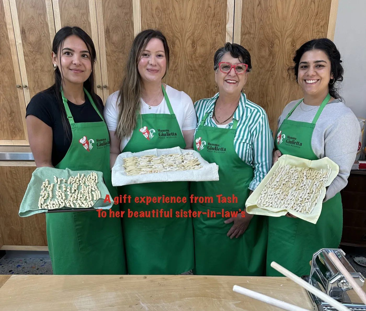 Mamma Giulietta with three guests holding trays of hand-shaped pasta at a gift workshop