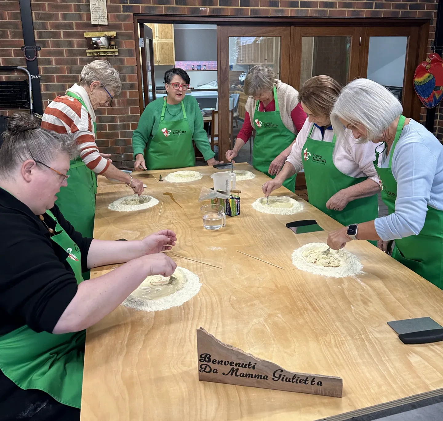 Workshop guests in Mamma Giulietta aprons making pasta dough wells