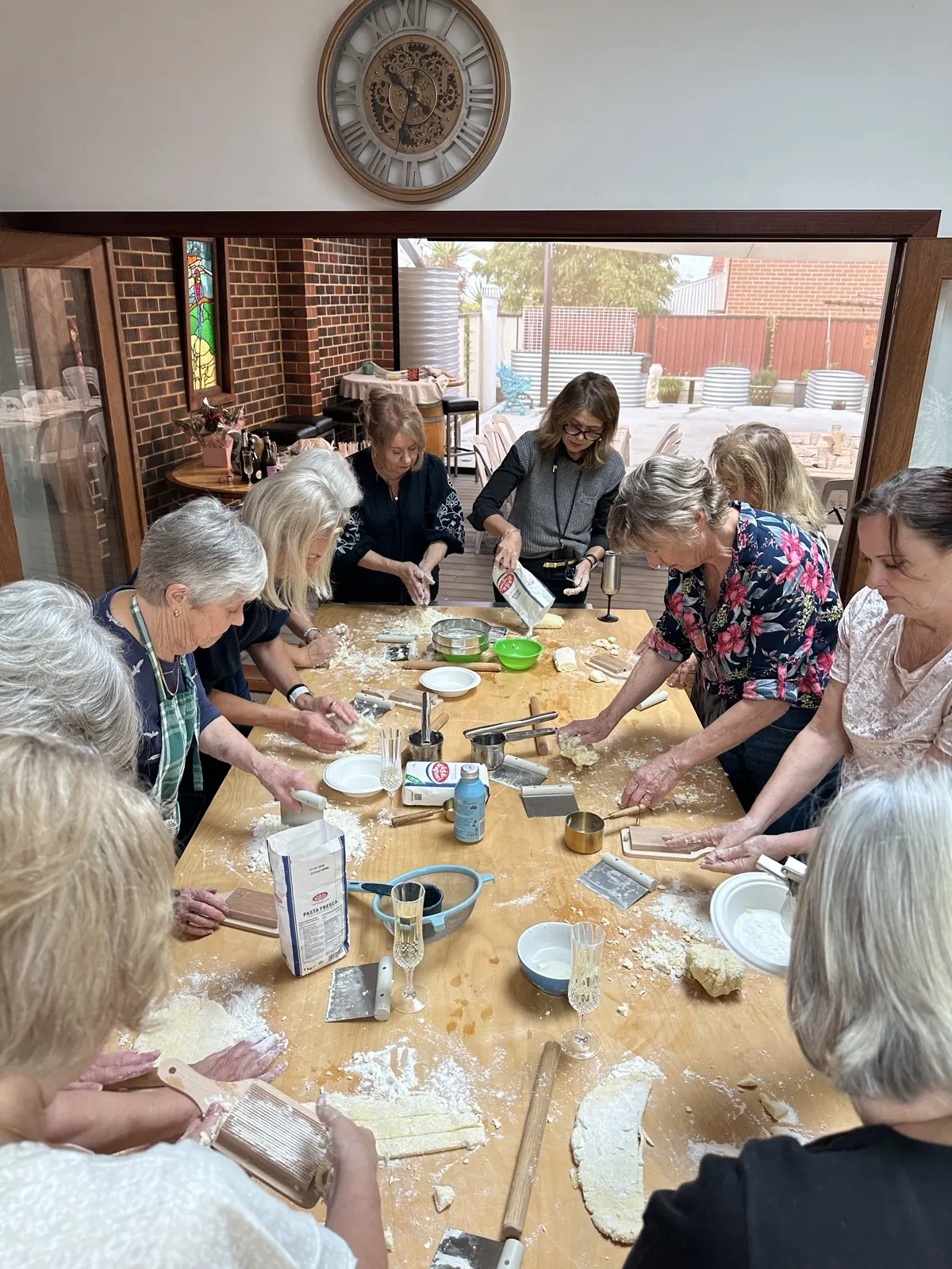 A group making fresh pasta together around the bench at a Mamma Giulietta workshop in Perth