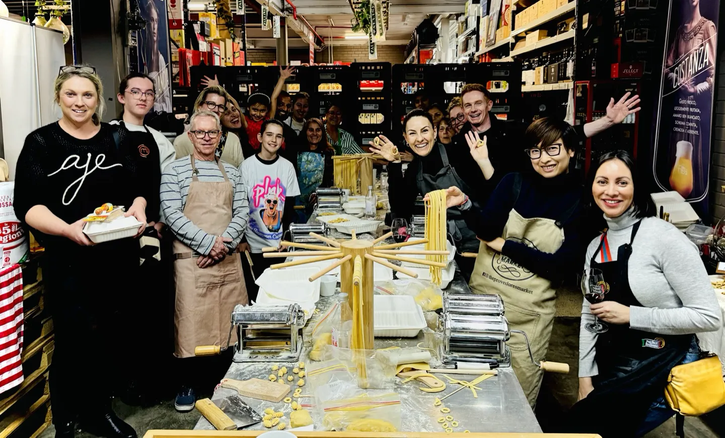A team building group celebrating with fresh pasta on a drying rack